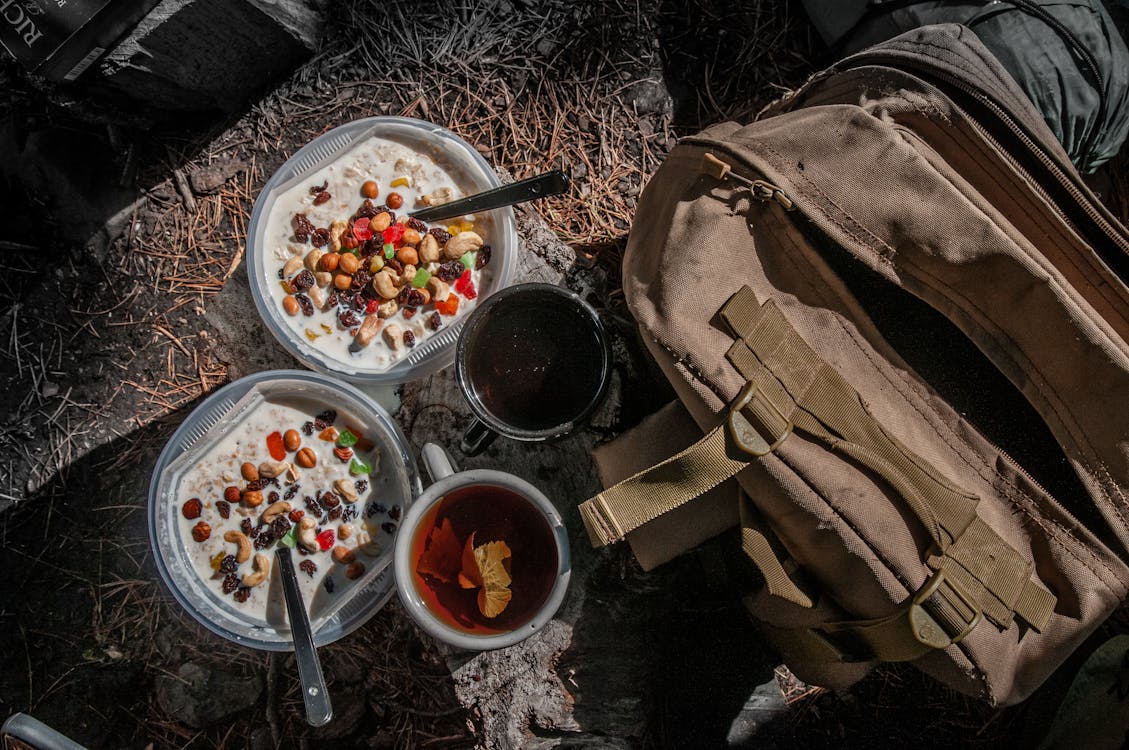 Opened freeze-dried food pouches and cans with prepared meals on a camp table
