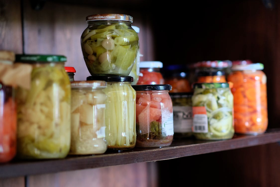 Well-organized pantry shelves with canned goods, mason jars, and labeled dry food storage bins