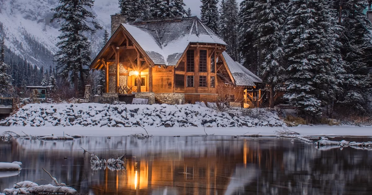 A rustic cabin with solar panels on the roof surrounded by trees and mountains