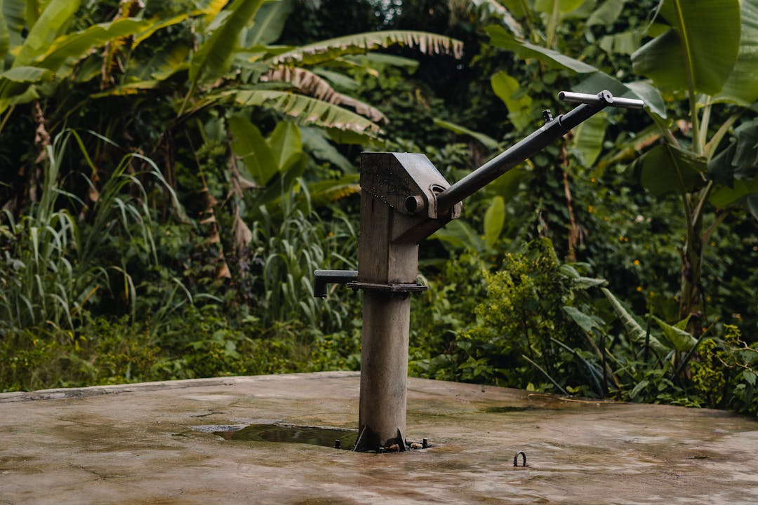 Hand pump well on rural off-grid property with clear water flowing