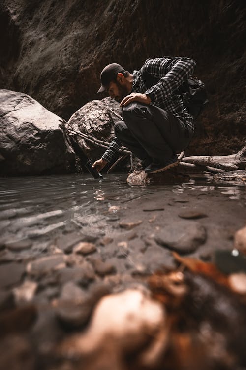 A person filtering water from a stream through a portable water filter into a metal bottle