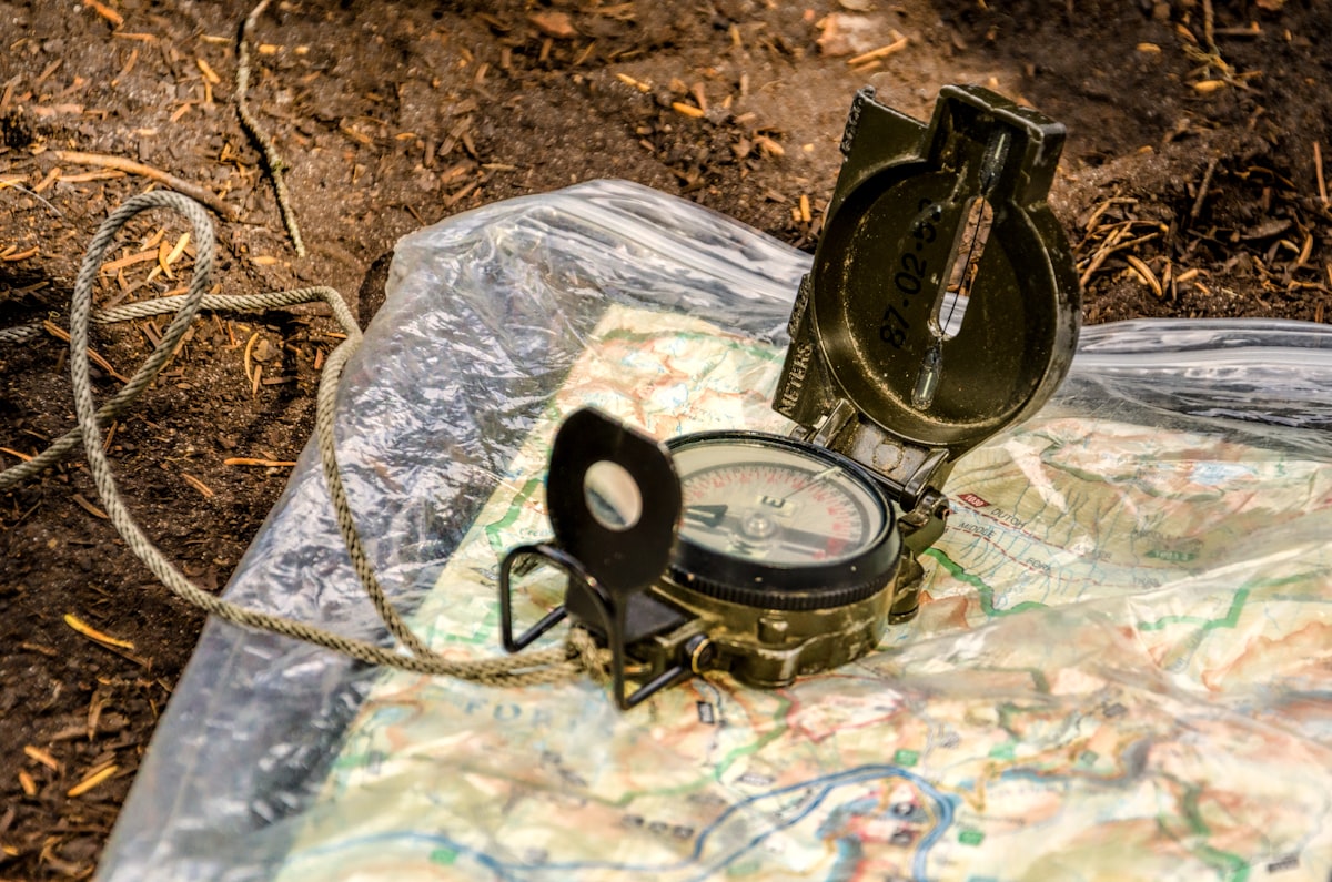 Topographic map spread on table with compass and pen marking evacuation route
