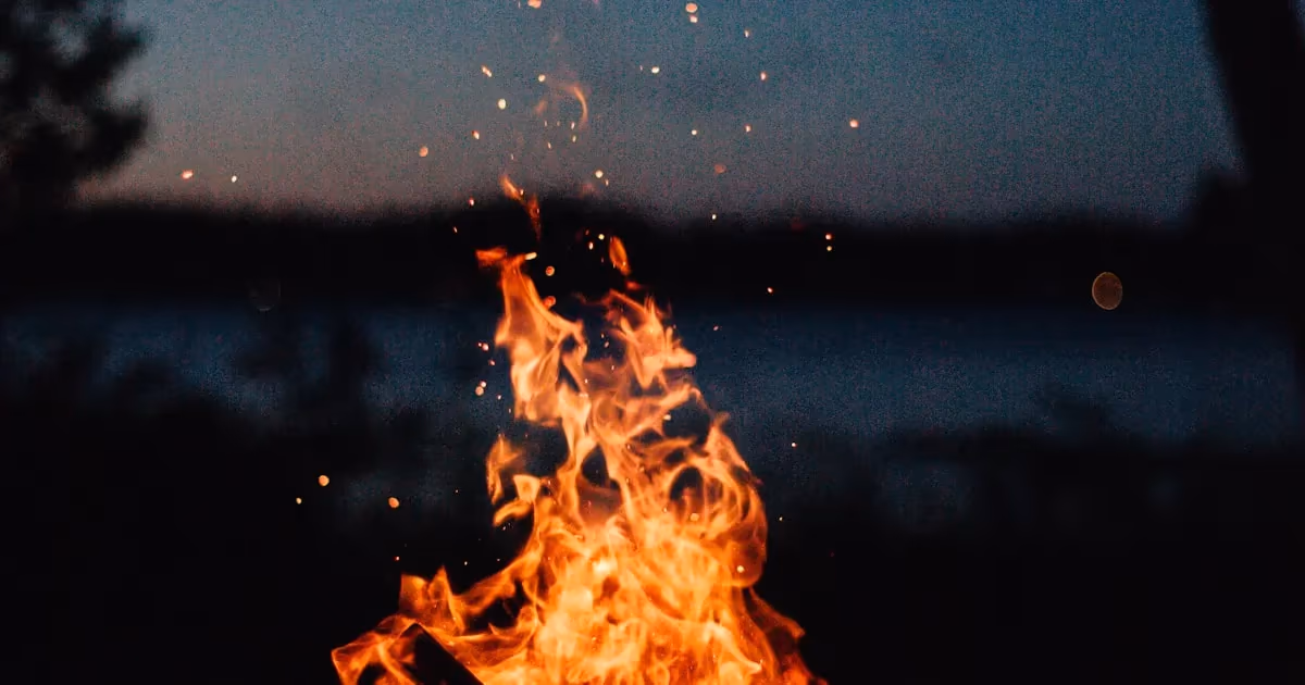 A small fire being started with a ferro rod sending sparks into tinder