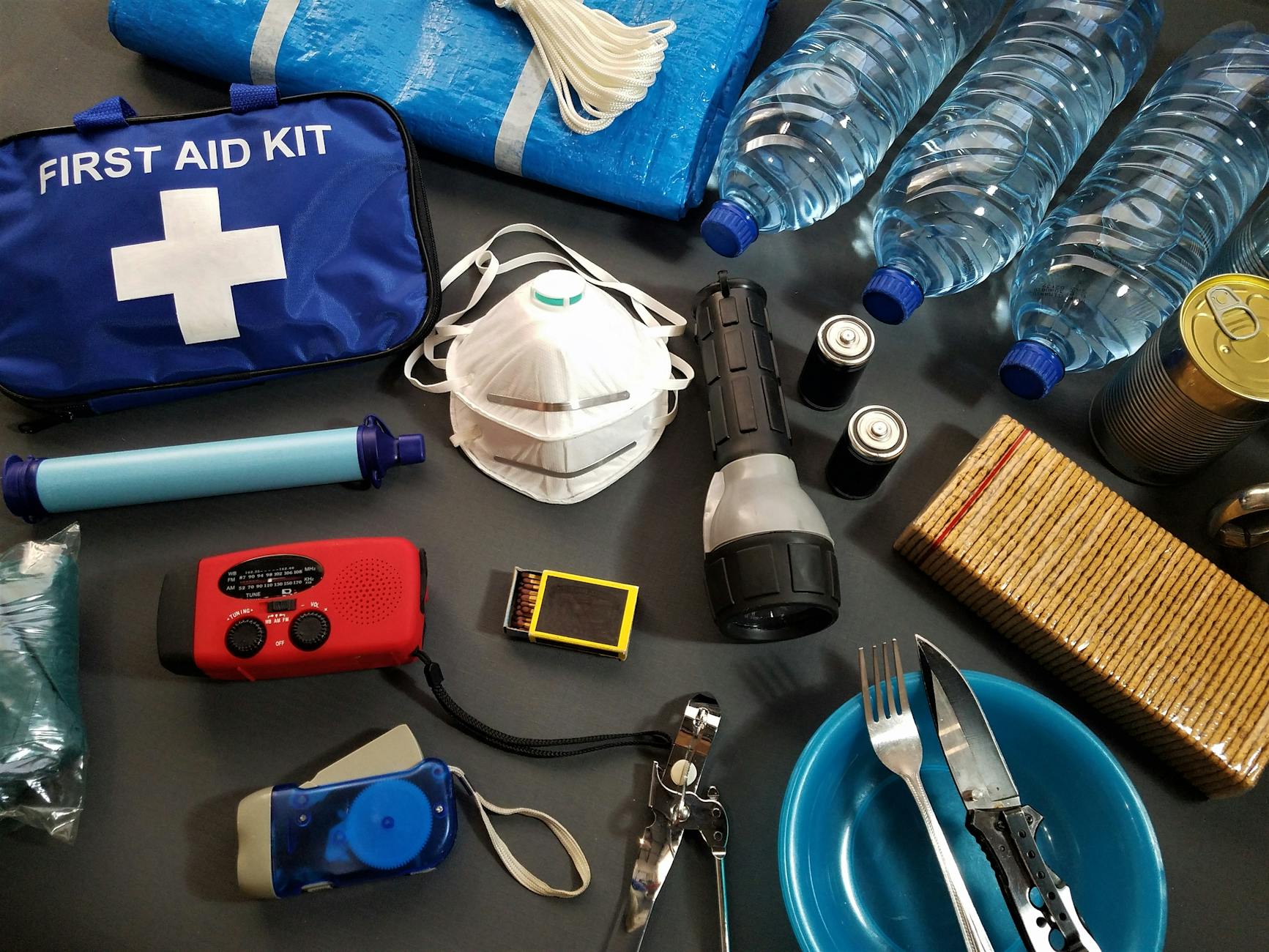 Organized emergency kit with food, water, first aid supplies laid out on a table