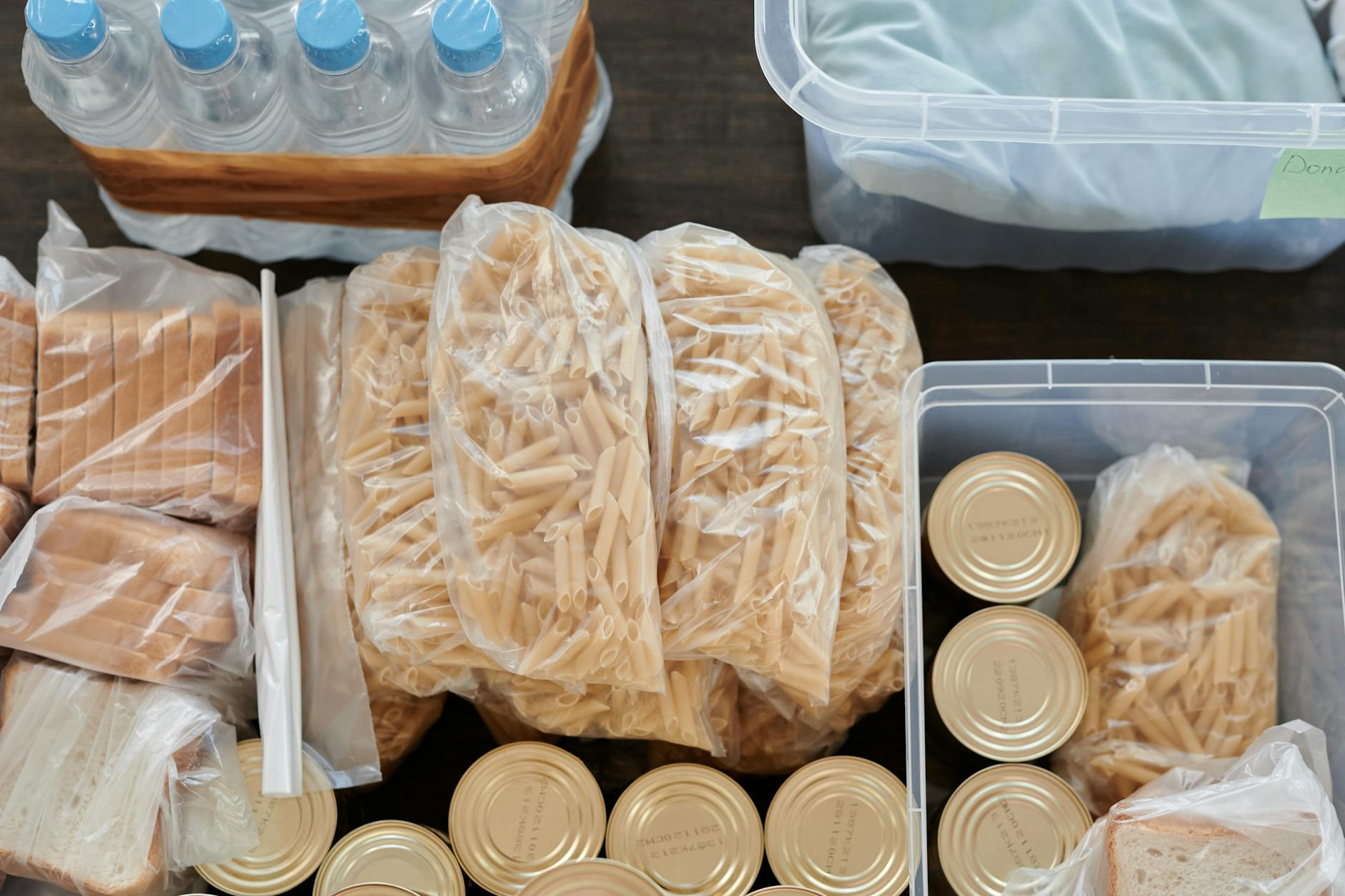 Survival food supplies including canned goods, dried beans, and energy bars on a shelf