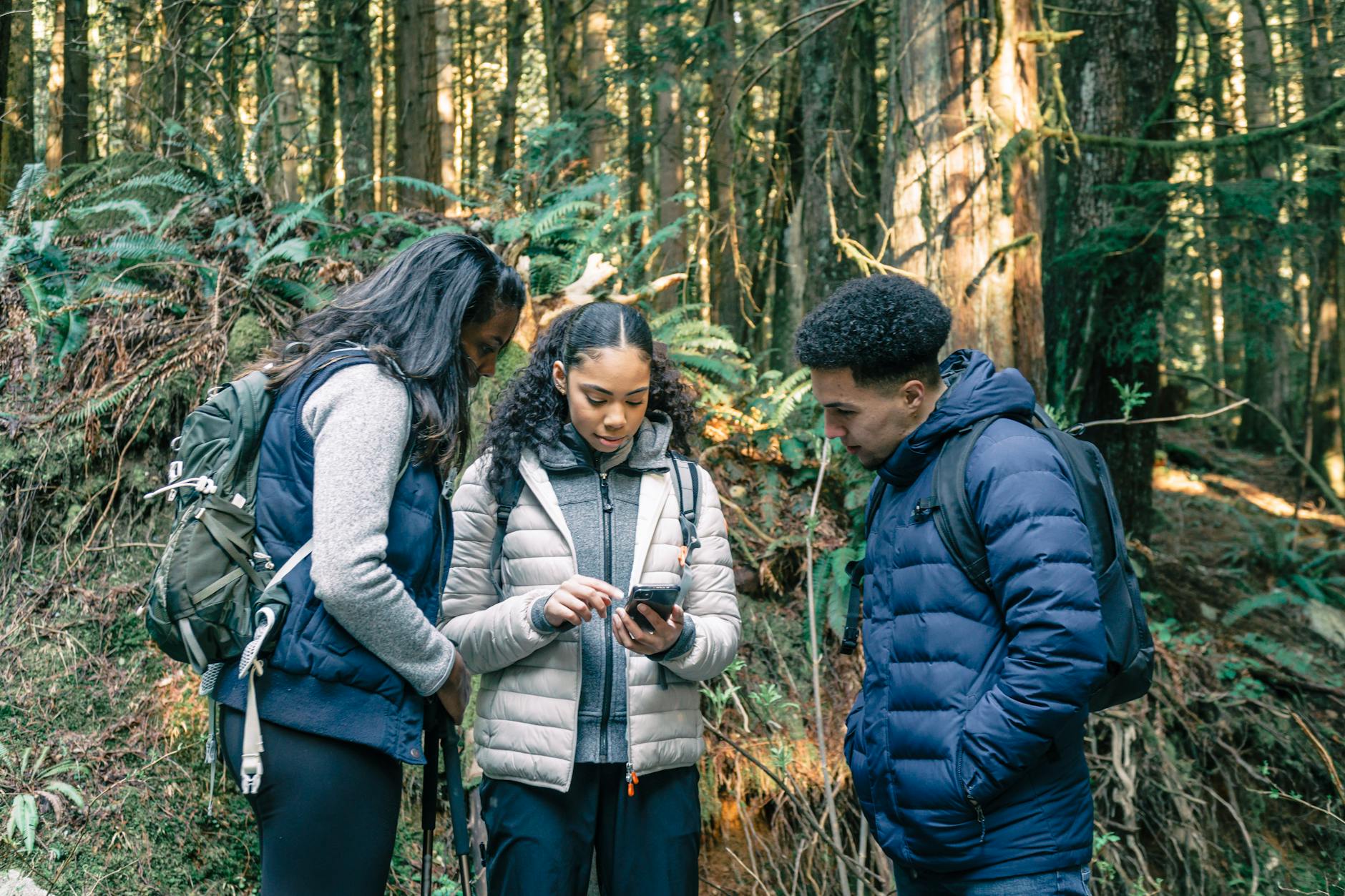 Person consulting a first aid guide on a phone while treating a minor injury on a hiking trail