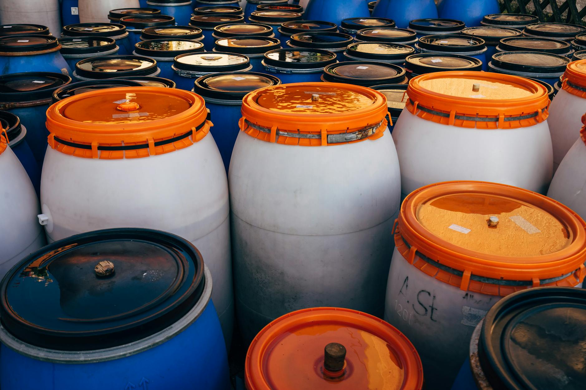 Large blue water storage containers lined up in a garage next to emergency supplies
