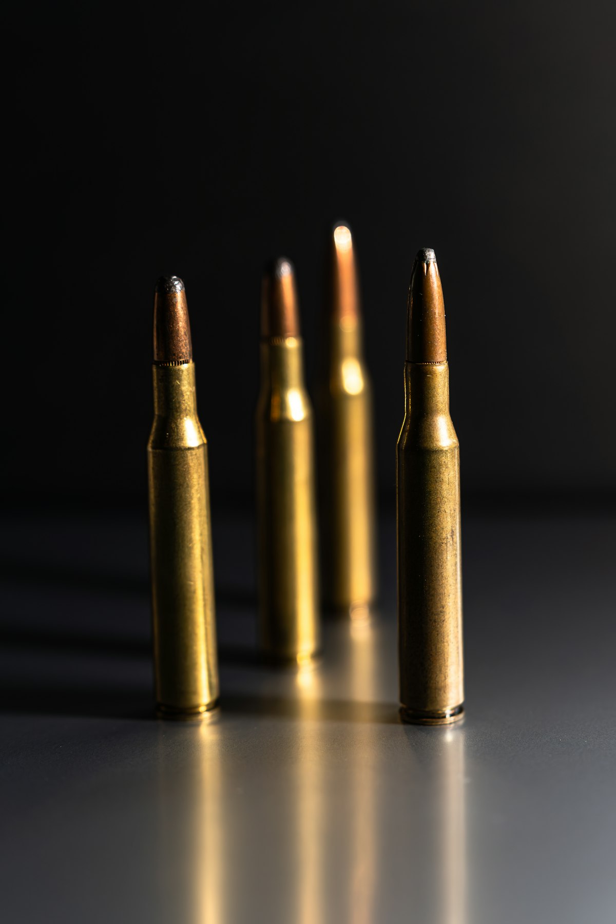 Row of common hunting rifle cartridges from left to right on a wooden surface including 308 30-06 and 6.5 Creedmoor