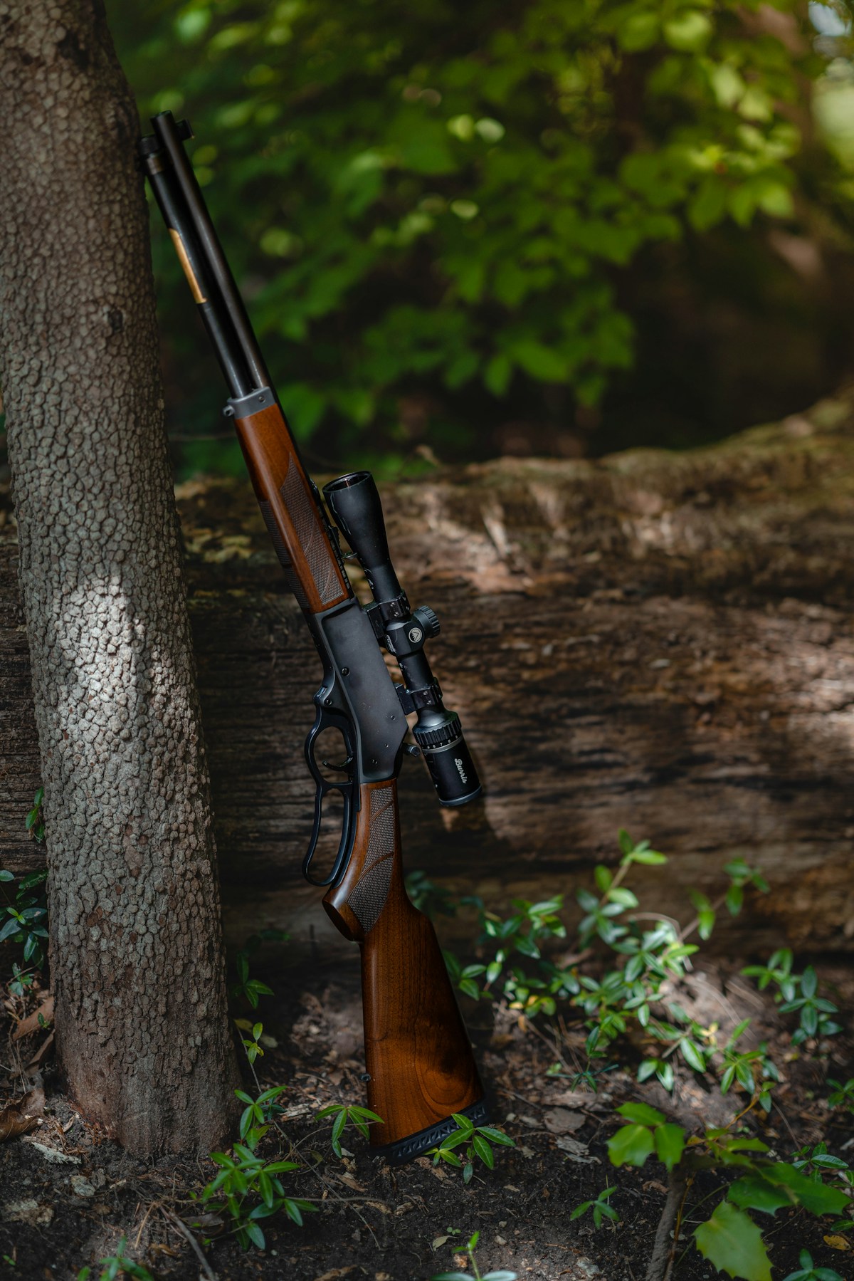 Bolt action hunting rifle with scope resting on a wooden surface next to rifle ammunition