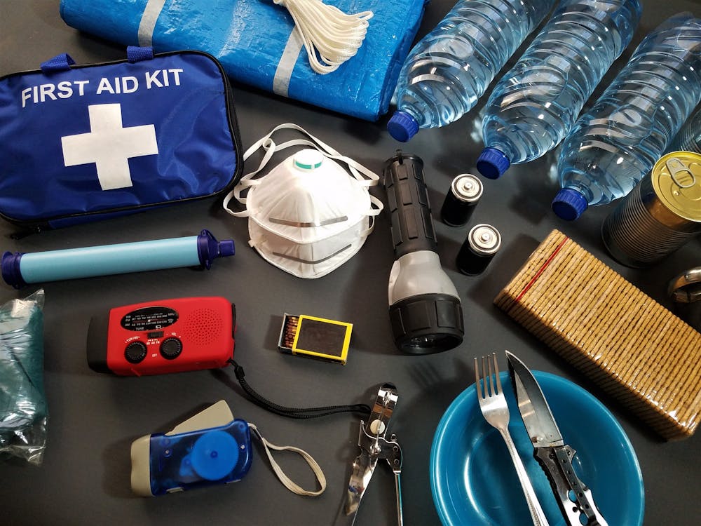 A table with affordable survival gear including water bottles, first aid supplies, and a flashlight
