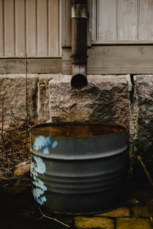 Large rainwater collection tanks connected to a metal roof with gutters and downspout filters