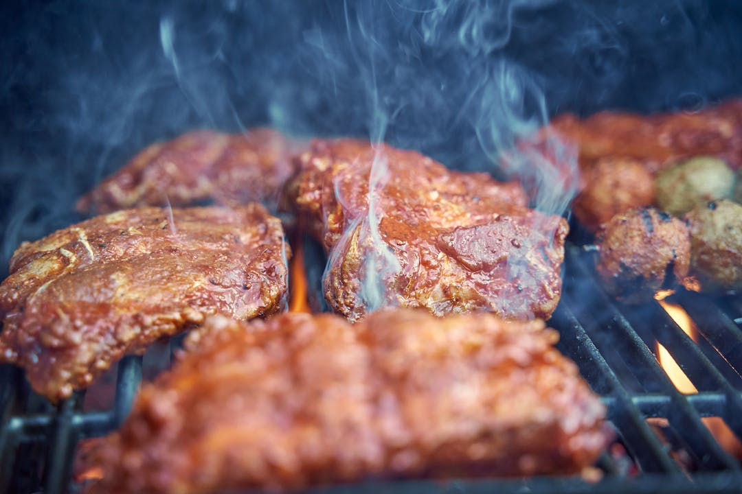 Meat hanging in a traditional smokehouse with visible wood smoke
