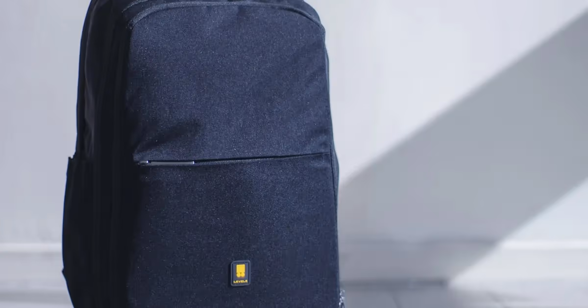 A compact backpack with survival essentials laid out next to a car steering wheel